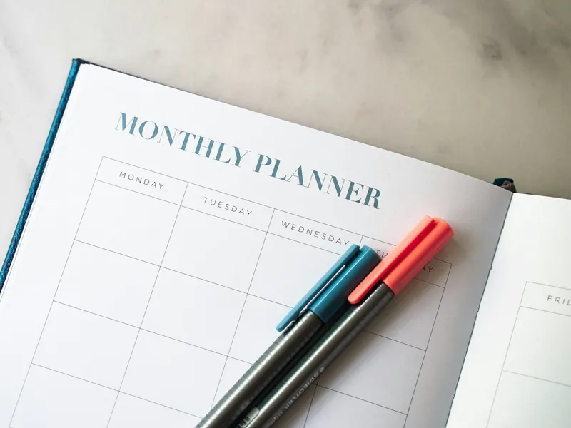 Un agenda papier ouvert avec deux stylos posés dessus