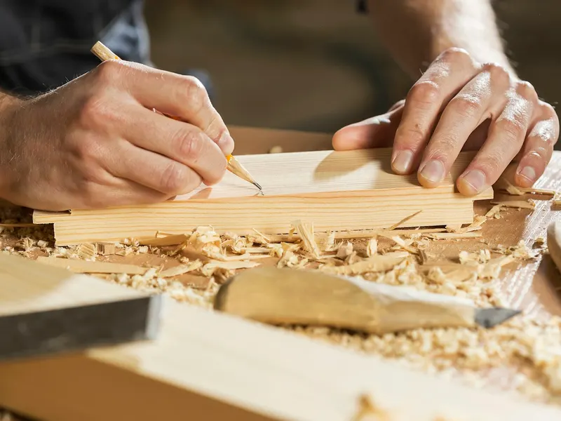 Un jeune menuisier travaille une pièce de bois dans son atelier