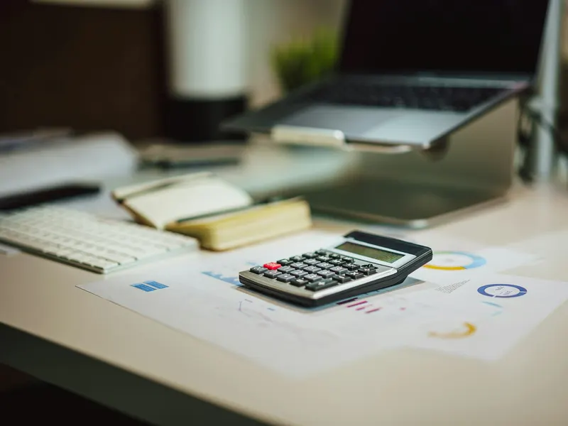 Une calculatrice posée sur une table à côté d'un ordinateur portable