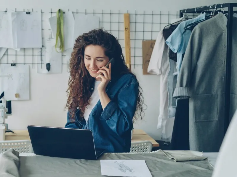 Une créatrice au téléphone dans son atelier, devant son ordinateur portable (photo Vitaly Gariev, Unsplash)