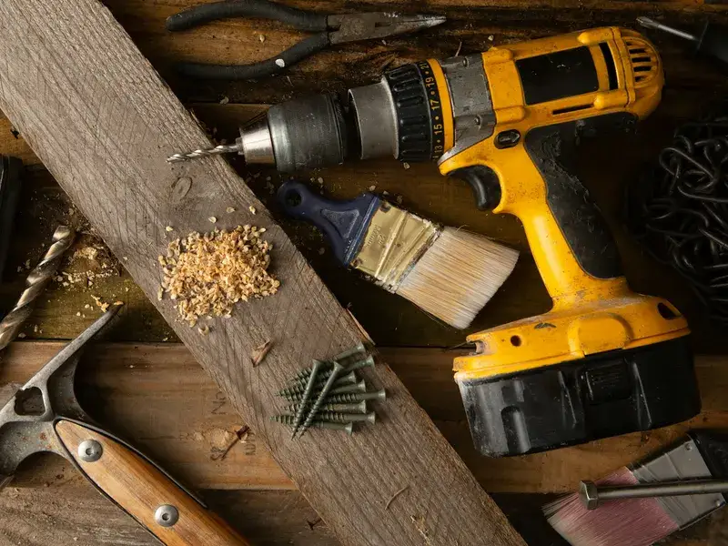 Un marteau, une perceuse et d'autres outils de rénovation posés sur une table