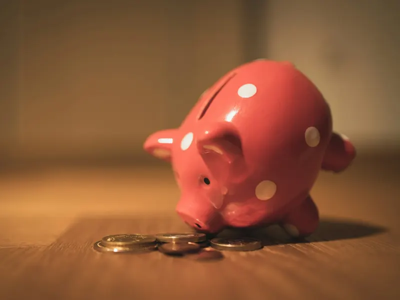Une tirelire en forme de cochon rose posée sur une table en bois